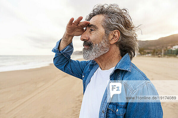 Senior man shielding eyes at beach