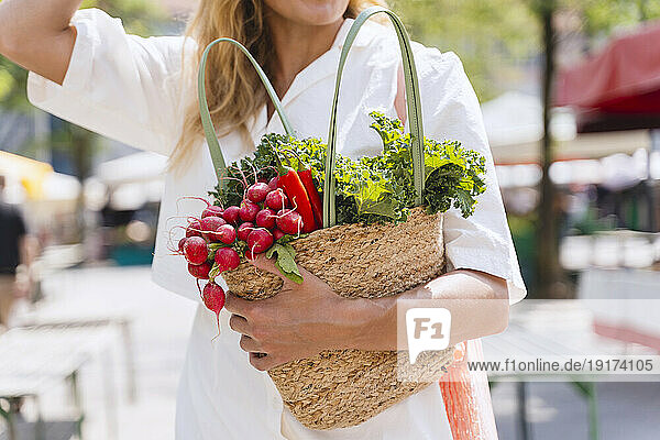 Woman holding bag of groceries in farmer's market