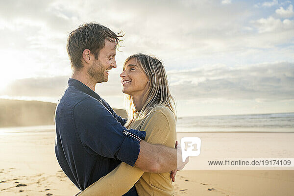 Smiling woman with man hugging each other at beach