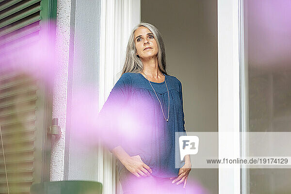 Thoughtful mature woman standing in doorway