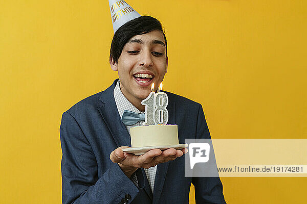 Happy man blowing candle on 18th birthday