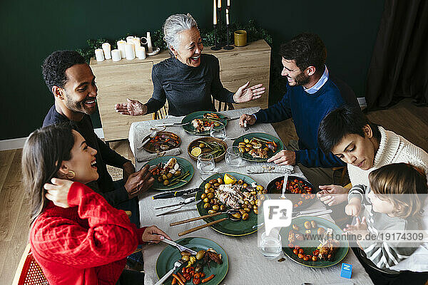 Cheerful multiracial family enjoying dinner party on Christmas