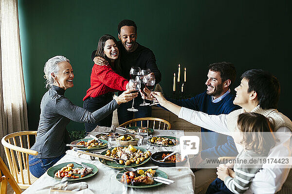 Cheerful family toasting wineglasses in dining room on Christmas