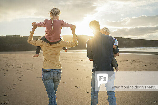 Mother and father walking with children at beach