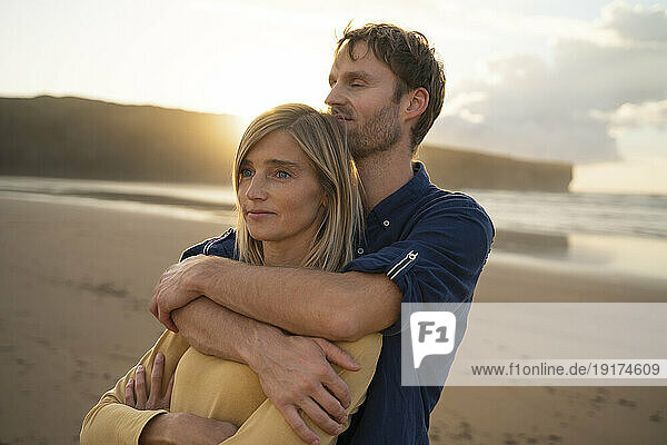 Man hugging thoughtful woman at beach