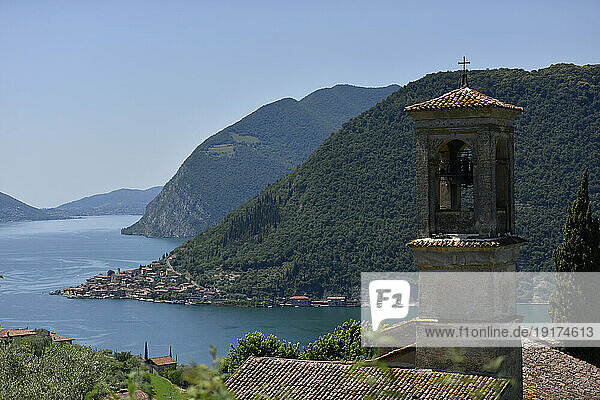 Italy  Lombardy  Lake Iseo surrounded by forested mountains with bell tower in foreground