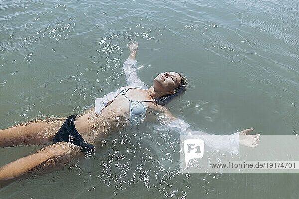 Woman floating on water in sea
