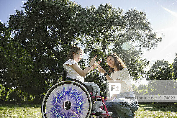 Happy daughter in wheelchair with mother at park on sunny day