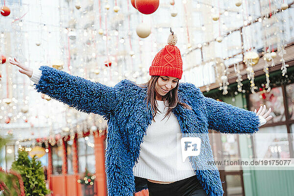Smiling woman wearing blue coat dancing in city