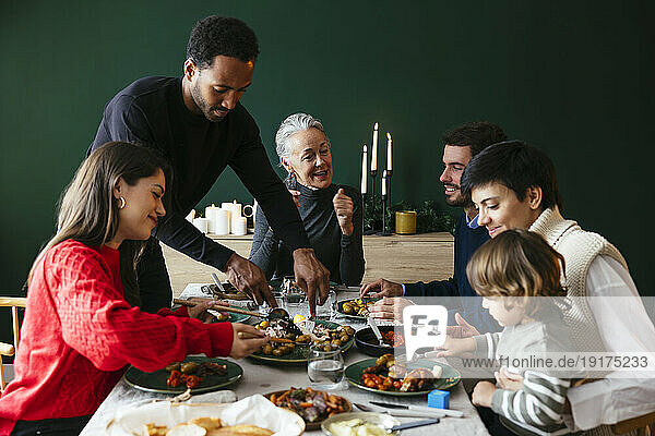 Multiracial family having dinner together at table in dining room