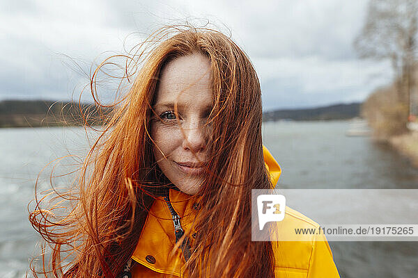 Redhead woman with long hair in front of lake