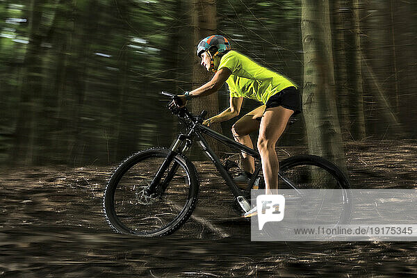 Adventurous athlete riding mountain bike in forest