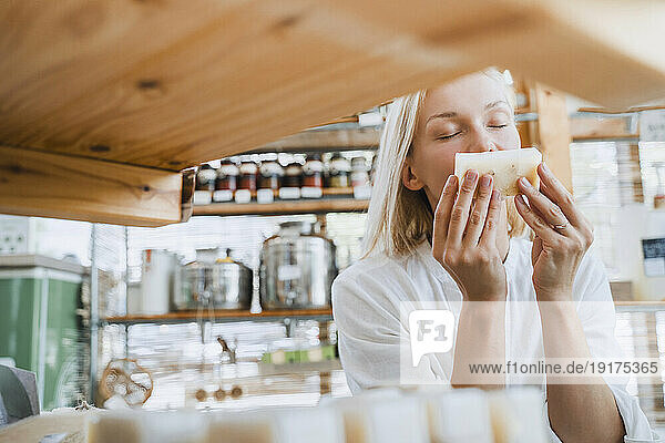 Blond woman smelling scented soap in shop