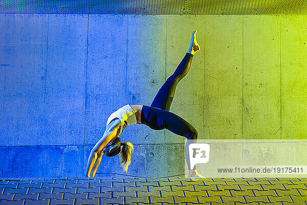 Woman exercising in front of neon colored wall