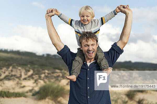 Happy father carrying son on shoulders at beach
