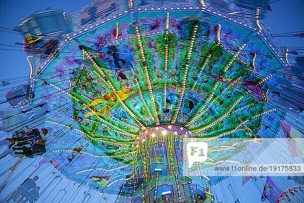 Germany  Bavaria  Wurzburg  Multiple exposure of spinning carousel at dusk