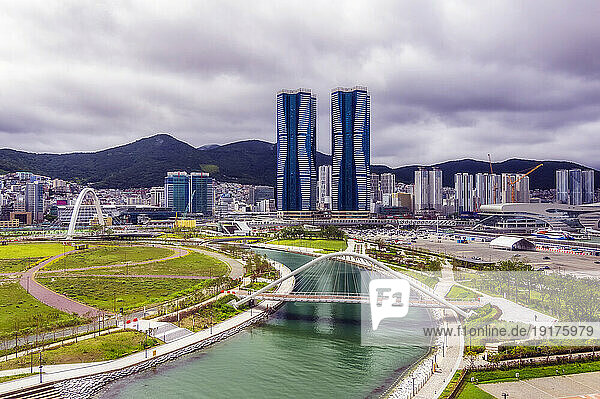 South Korea  Busan  Cloudy sky over bridge over river flowing through city park