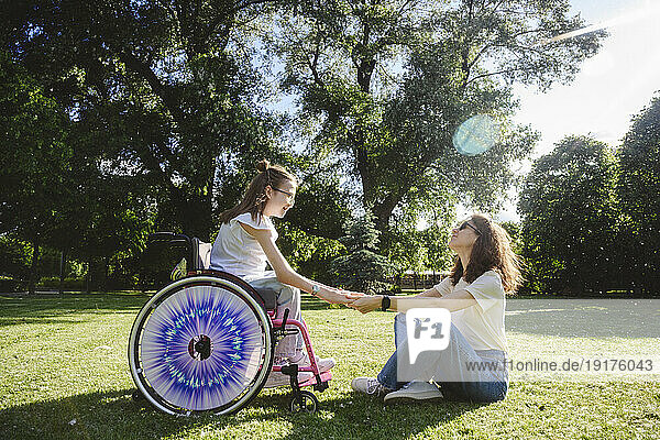 Mother spending leisure time with daughter sitting in wheelchair