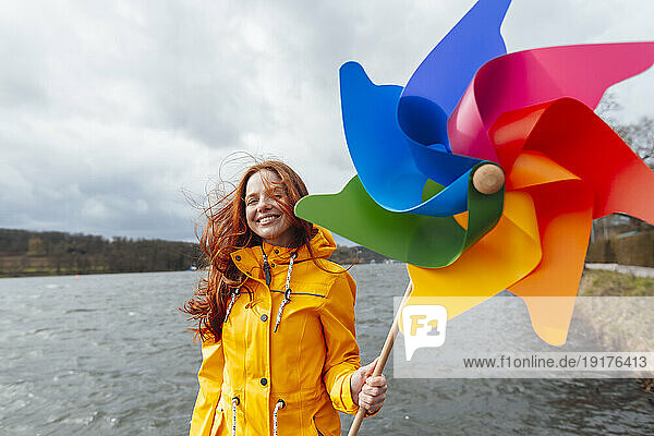 Smiling woman with pinwheel toy in front of lake
