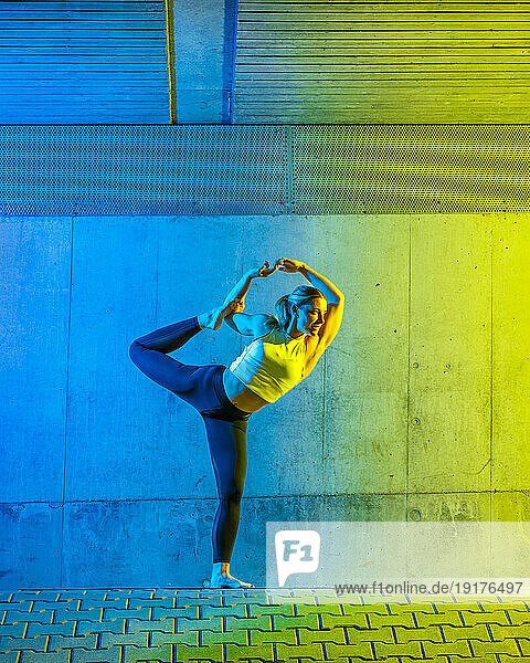 Woman doing yoga in front of neon colored wall
