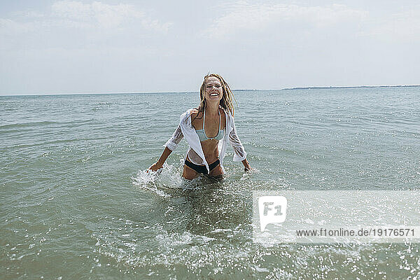 Happy playful woman splashing water in sea