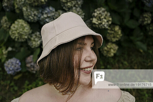 Smiling woman wearing bucket hat in garden