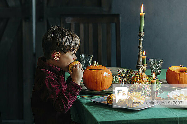 Boy eating sweetcorn at dining table