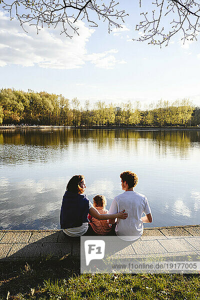 Mother with daughter and son sitting by lake in park