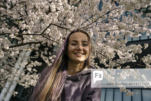 Happy woman in front of blooming cherry tree at park