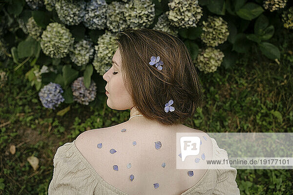 Young woman with flower petals on back in garden