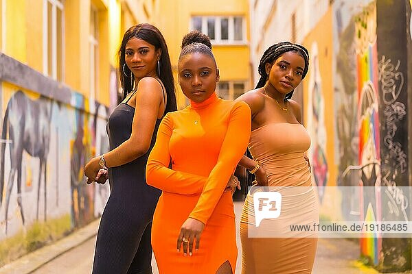San Sebastián  Gipuzkoa Spanien  Februar 2021: Modischer urbaner Stil mit drei schwarzafrikanischen Mädchen auf einer Stadtstraße  enge Kleider und verführerische Looks. Lifestyle Girls of Color