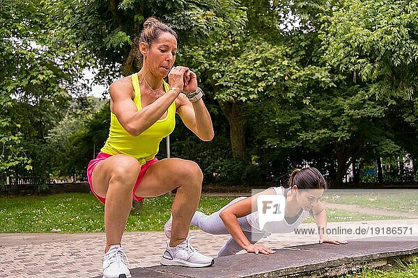 Latino Mädchen beim Sport in einem Park in der Stadt  Lifestyle ein gesundes Leben  zwei Mädchen tun Stretching und Kniebeugen