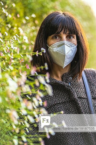 Porträt einer jungen Frau mit einer Maske neben einem schönen Gänseblümchen. Erste Spaziergänge der unkontrollierten Covid 19 Pandemie