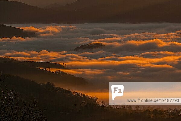 Morgendämmerung mit dichtem orangefarbenem Nebel an einem Wintermorgen in Agina. Baskenland