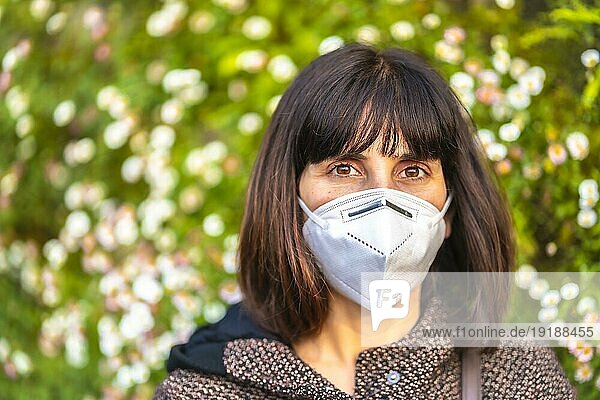Porträt einer jungen Frau mit einer Maske neben einem schönen Gänseblümchen. Erste Spaziergänge der unkontrollierten Covid 19 Pandemie