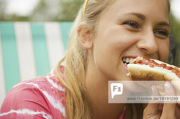 Close up of a teenaged girl eating a hot dog