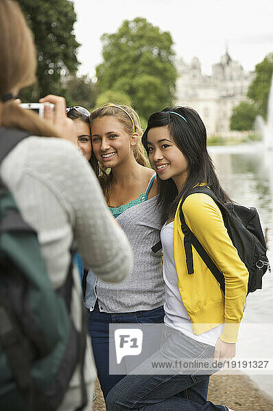 Back view of woman taking photograph of three teenaged girls