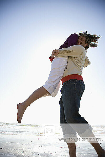 Young couple playing and messing around on a beach
