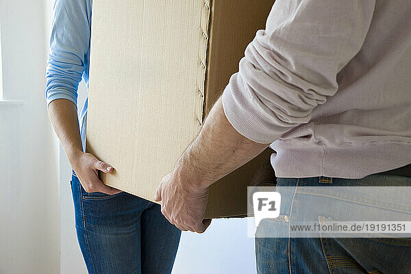 Close up of a couple hands carrying cardboard box