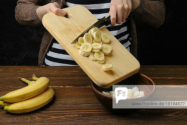 Unbekannte Frau legt geschnittene Banane in eine Schüssel