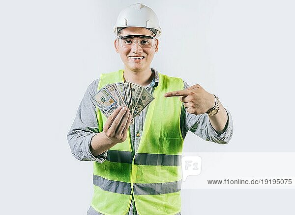 Lächelnde Ingenieur Bauherr hält und zeigt Geld isoliert. Handsome Ingenieur zeigt und zeigt Geld isoliert