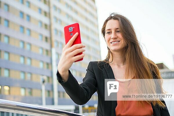 Lächelnde lässige Geschäftsfrau  die ein Selfie mit dem Handy im Freien macht