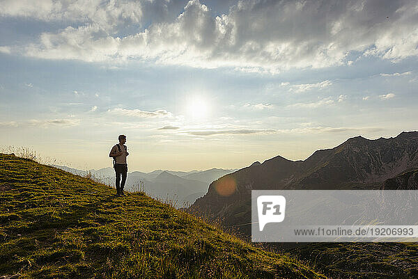Germany  Bavaria  Oberstdorf  man on a hike in the mountains looking at view at sunset