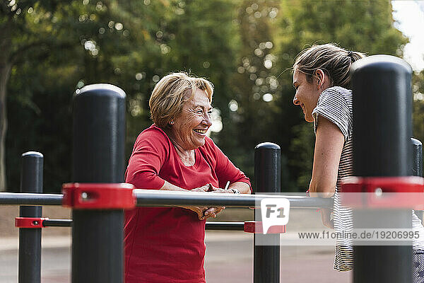 Grandmother and granddaughter training on bars in a park