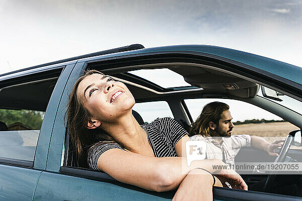 Smiling young woman leaning out of car window