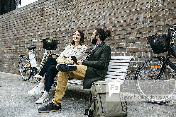 Couple sitting on a bench next to e-bikes talking