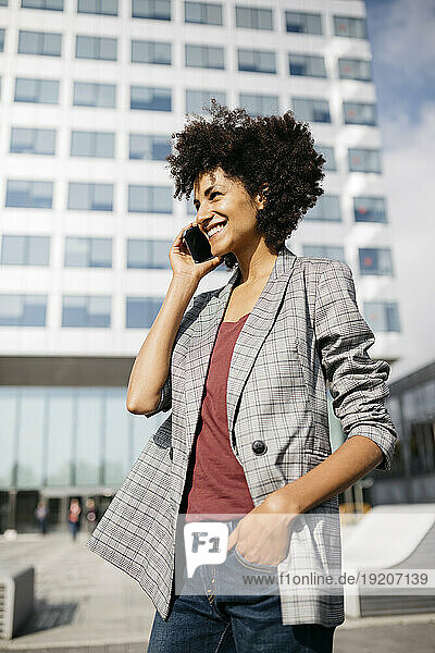 Smiling businesswoman on cell phone outside office building
