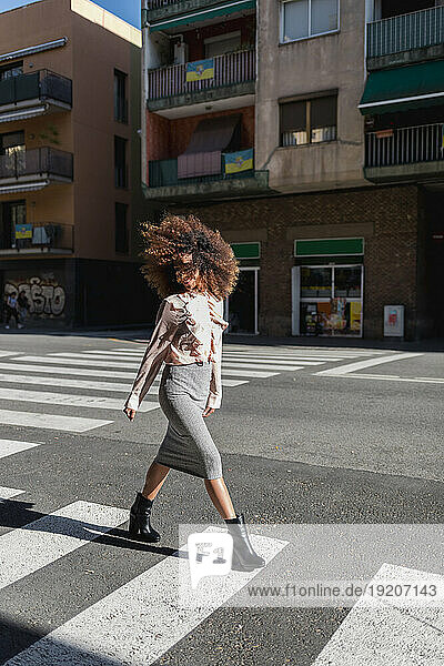 Young woman with afro hairdo crossing the street in the city
