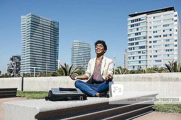 Businesswoman sitting on bench and meditating