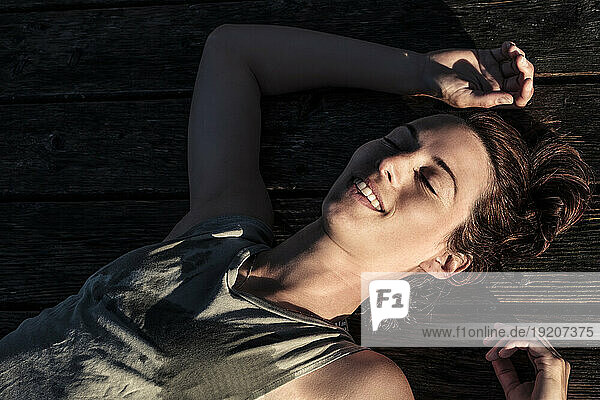 Portait of a happy woman lying on a jetty in sunlight